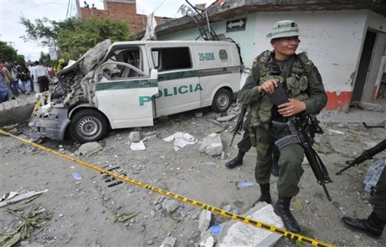 A police officer stands next to a police vehicle damaged during home made mortars attack to the police station in Villa Rica, southwest Colombia, Thursday, Feb. 2, 2012. The police post's commander and at least five civilians died during the attack, that came a day after a bomb in the Pacific port of Tumaco killed nine people. (AP Photo/Carlos Julio Martinez)